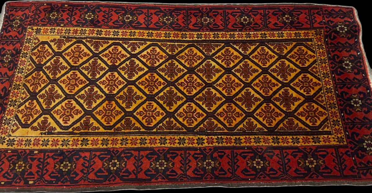 alfombra persa de estilo baluch en dimensiones 176 centímetros de largo por 91 centímetros de ancho con colores principalmente naranja y amarillo — Perspectiva
