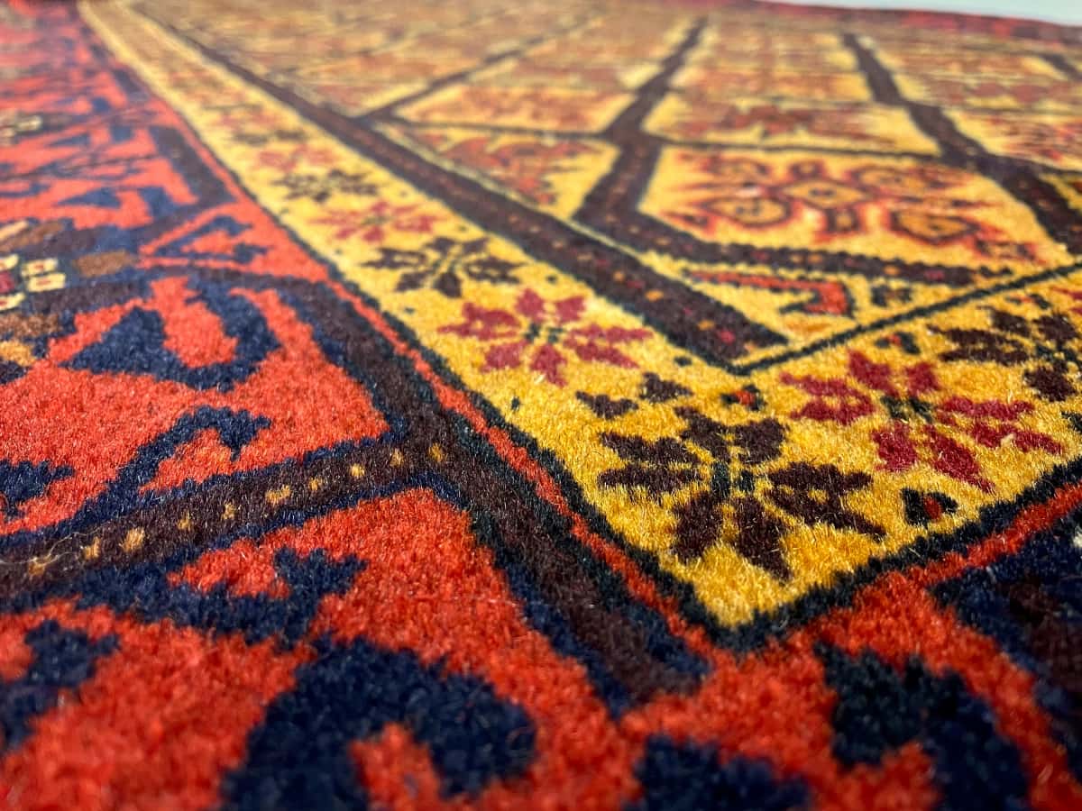 persischer Teppich im Baluch Stil in den Maßen 176 Zentimeter Länge mal 91 Zentimeter Breite mit überwiegend orange und gelb Farben — Nahaufnahme der Textur