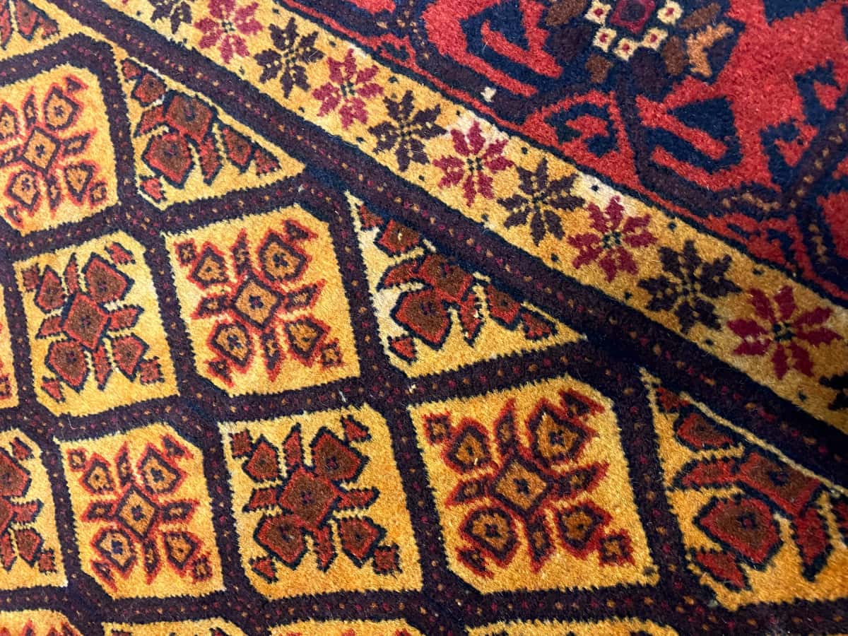 persischer Teppich im Baluch Stil in den Maßen 176 Zentimeter Länge mal 91 Zentimeter Breite mit überwiegend orange und gelb Farben — Nahaufnahme der Textur
