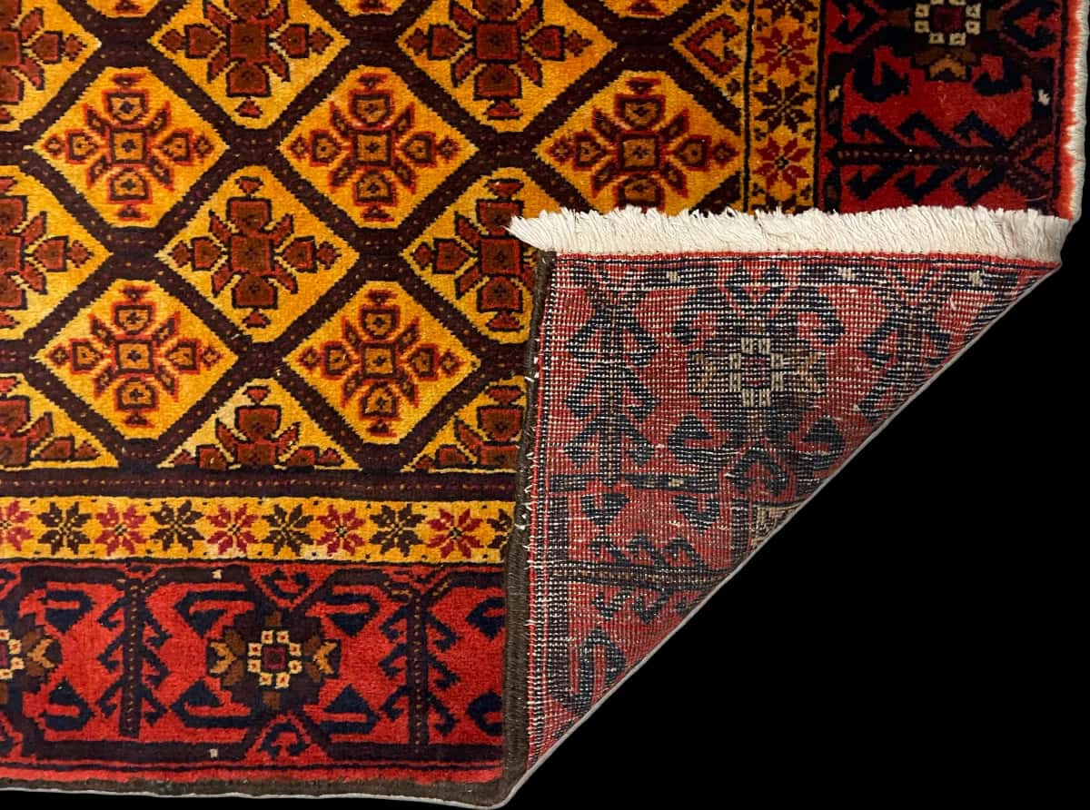 persischer Teppich im Baluch Stil in den Maßen 176 Zentimeter Länge mal 91 Zentimeter Breite mit überwiegend orange und gelb Farben — Gefaltet