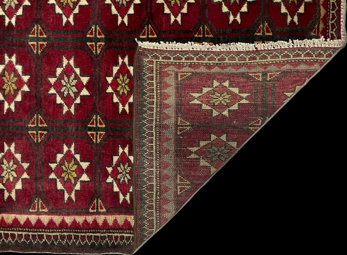 alfombra persa de estilo baluch en dimensiones 150 centímetros de largo por 92 centímetros de ancho con colores principalmente rojo — Plegada