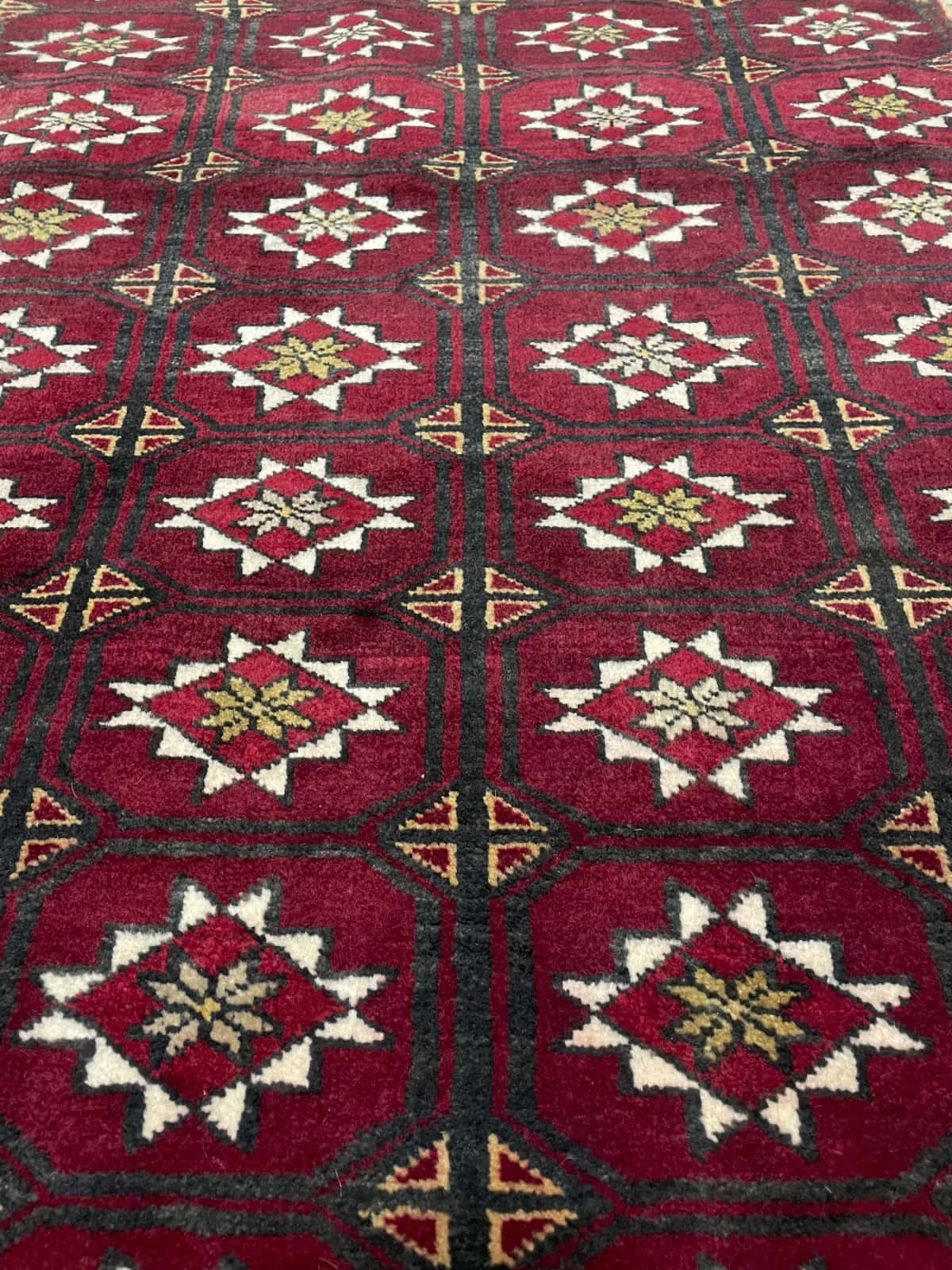 alfombra persa de estilo baluch en dimensiones 150 centímetros de largo por 92 centímetros de ancho con colores principalmente rojo — Primer plano de la textura