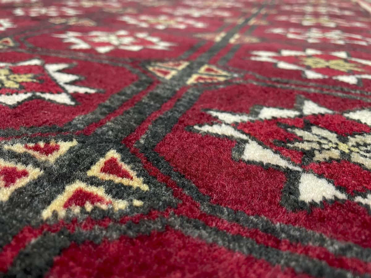 alfombra persa de estilo baluch en dimensiones 150 centímetros de largo por 92 centímetros de ancho con colores principalmente rojo — Primer plano de la textura