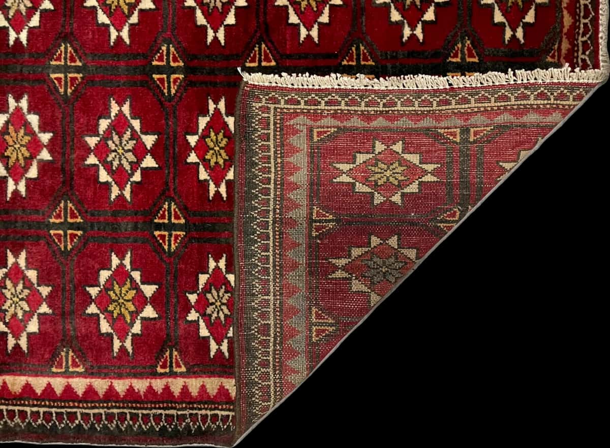 persischer Teppich im Baluch Stil in den Maßen 150 Zentimeter Länge mal 92 Zentimeter Breite mit überwiegend rot Farben — Gefaltet