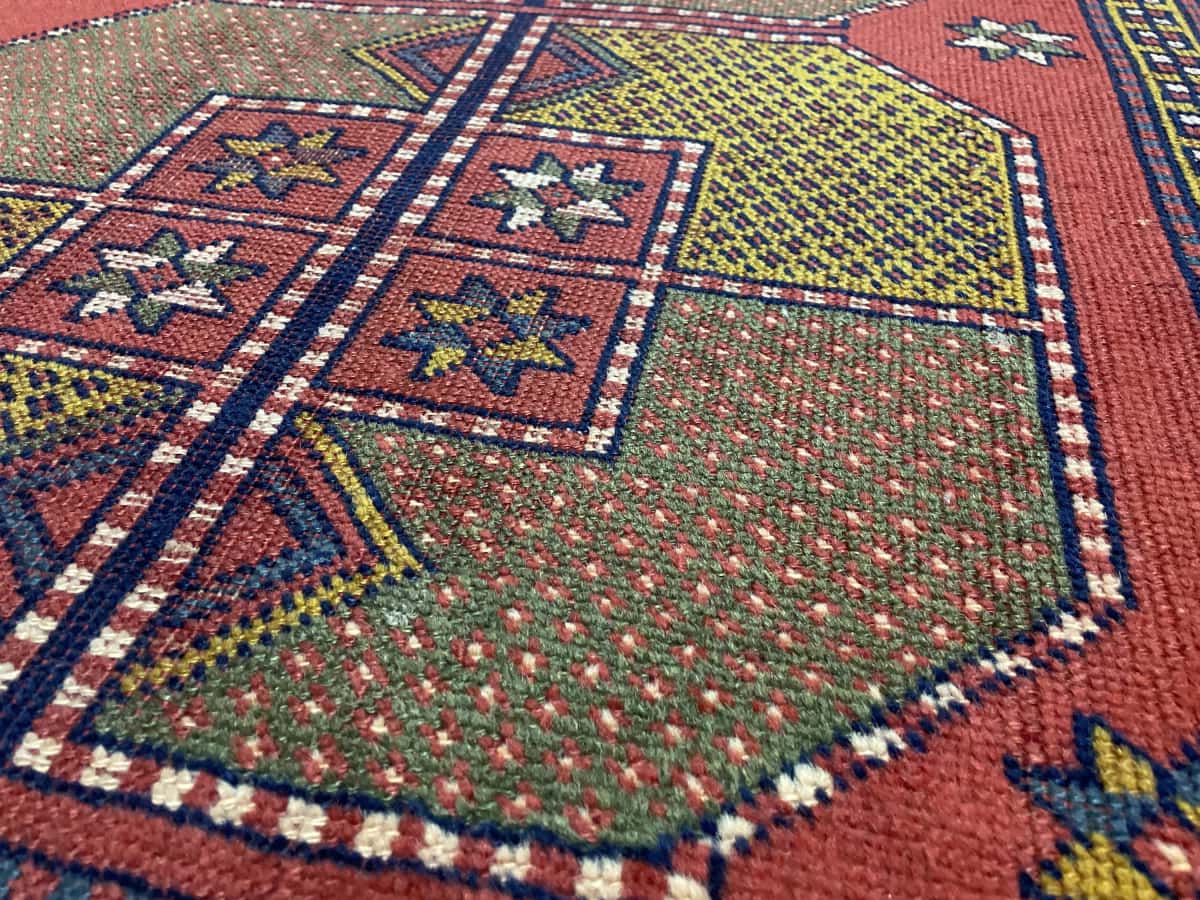 Persian rug of Baluch style in dimensions 187 centimeters length by 110 centimeters width with mainly red colors — Texture close-up