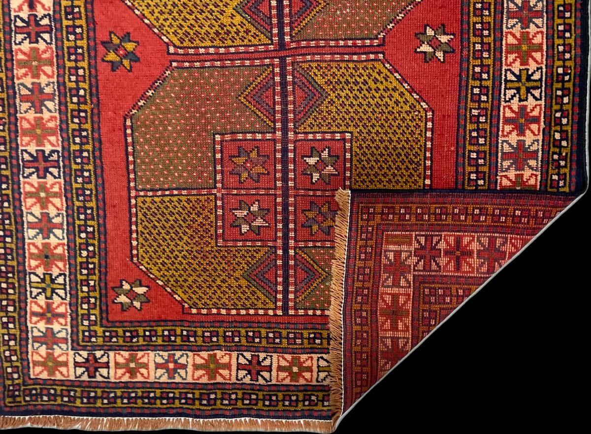persischer Teppich im Baluch Stil in den Maßen 187 Zentimeter Länge mal 110 Zentimeter Breite mit überwiegend rot Farben — Gefaltet