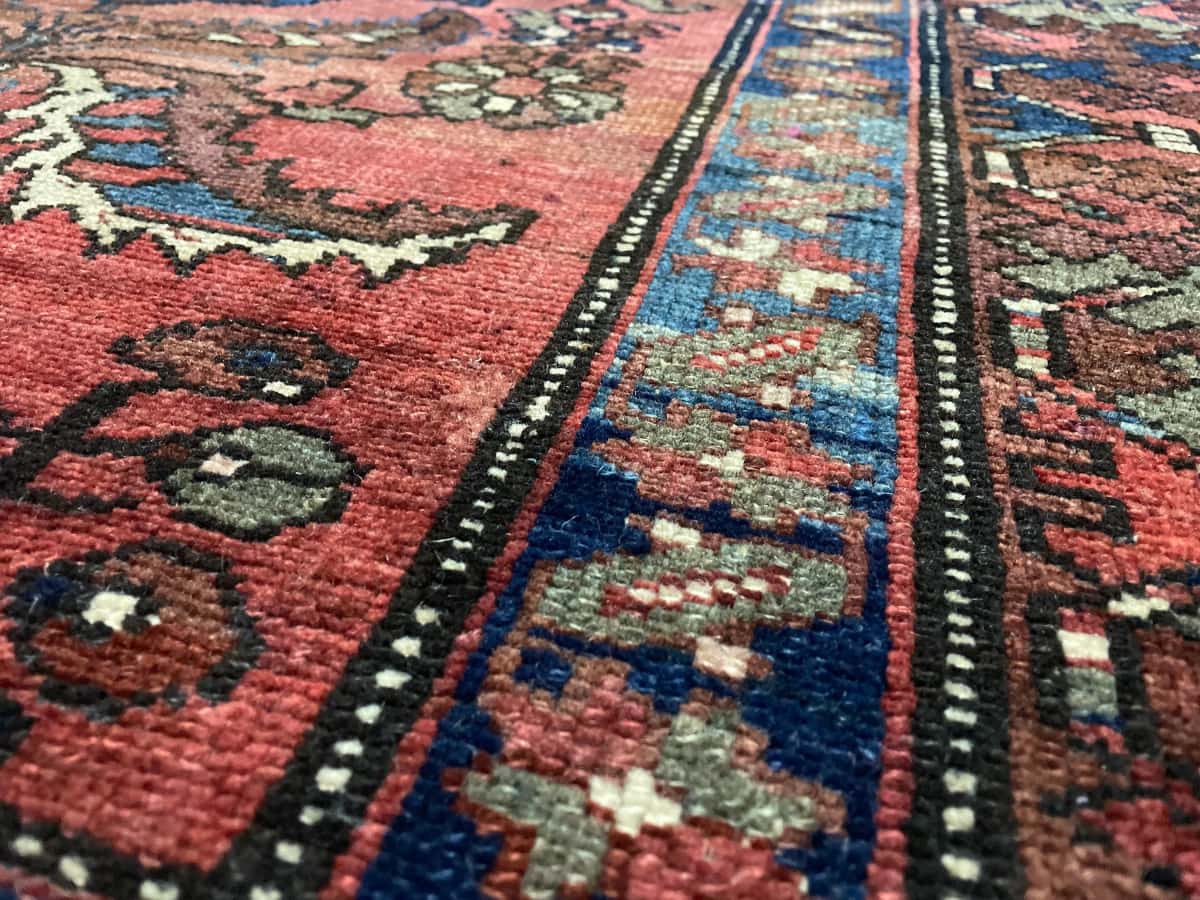 alfombra persa de estilo bakhtiari en dimensiones 200 centímetros de largo por 137 centímetros de ancho con colores principalmente rojo — Primer plano de la textura