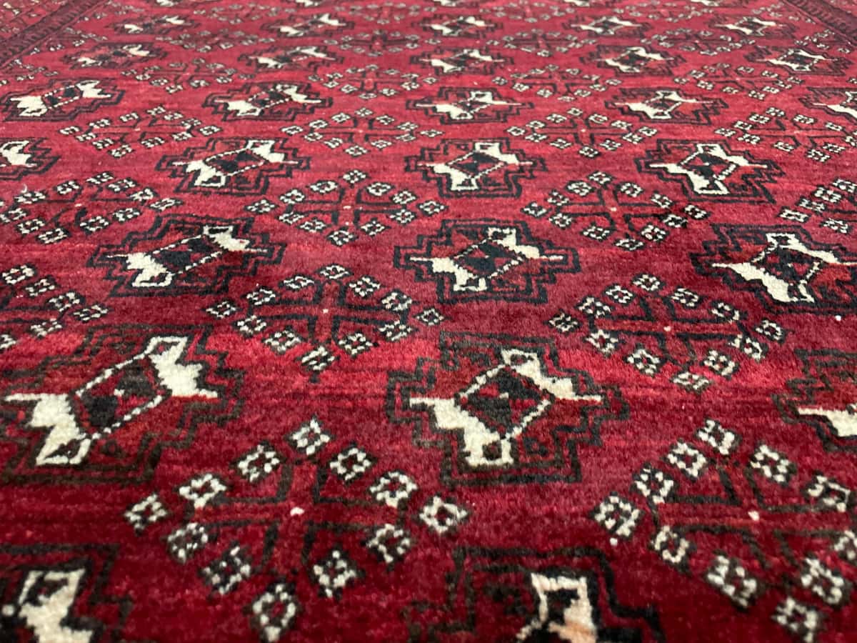 Persian rug of Baluch style in dimensions 218 centimeters length by 106 centimeters width with mainly red colors — Texture close-up