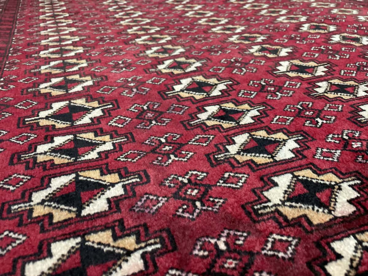 Persian rug of Baluch style in dimensions 204 centimeters length by 116 centimeters width with mainly red colors — Texture close-up