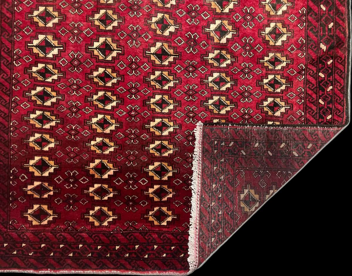 persischer Teppich im Baluch Stil in den Maßen 204 Zentimeter Länge mal 116 Zentimeter Breite mit überwiegend rot Farben — Gefaltet