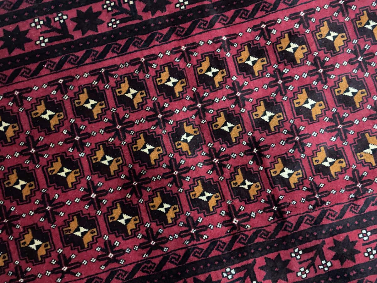 Persian rug of Baluch style in dimensions 200 centimeters length by 100 centimeters width with mainly red colors — Texture close-up