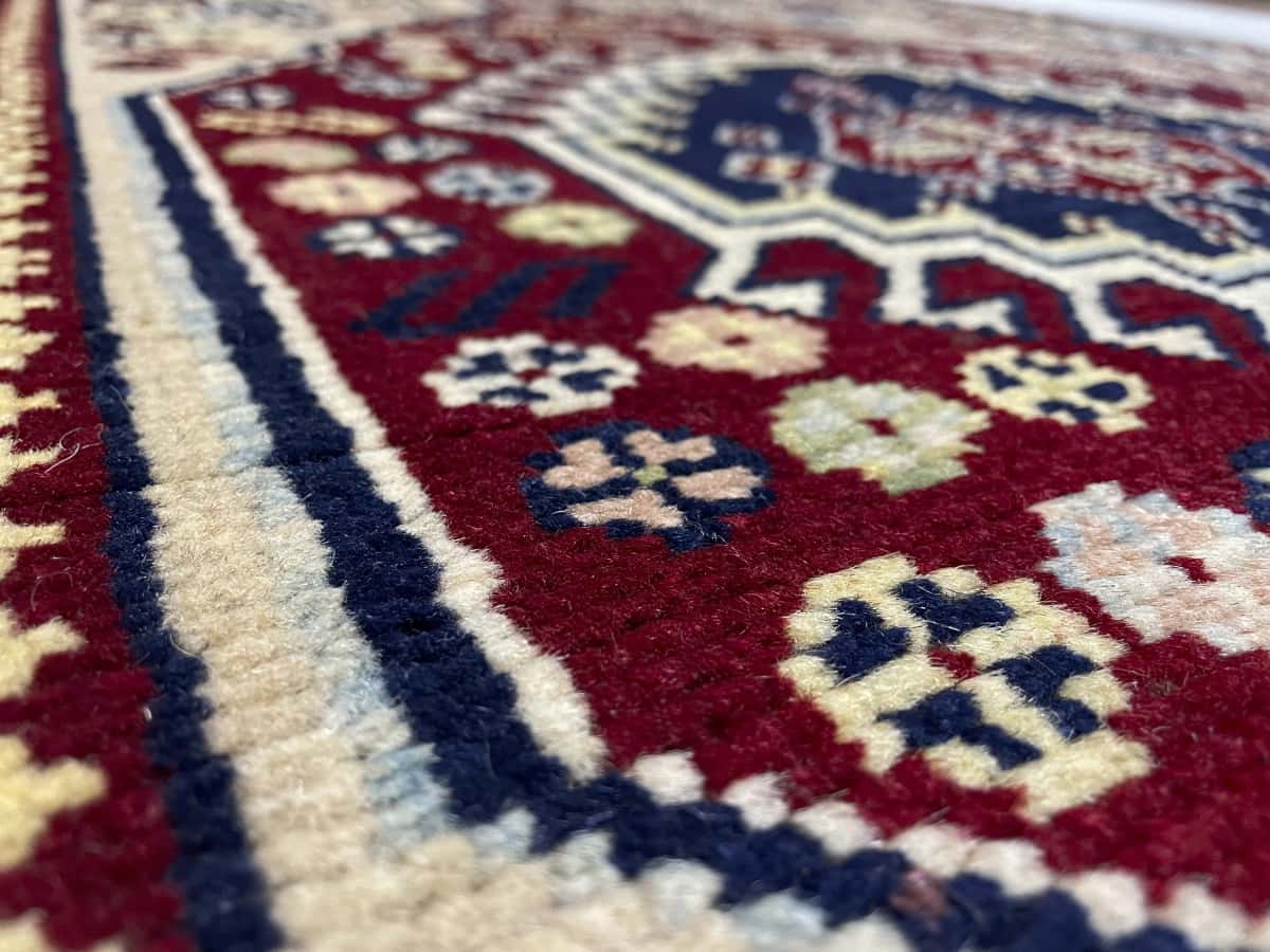 Persian rug of Baluch style in dimensions 145 centimeters length by 103 centimeters width with mainly beige and red colors — Texture close-up