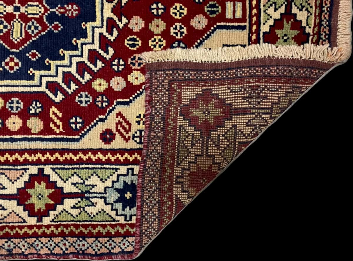 persischer Teppich im Baluch Stil in den Maßen 145 Zentimeter Länge mal 103 Zentimeter Breite mit überwiegend beige und rot Farben — Gefaltet