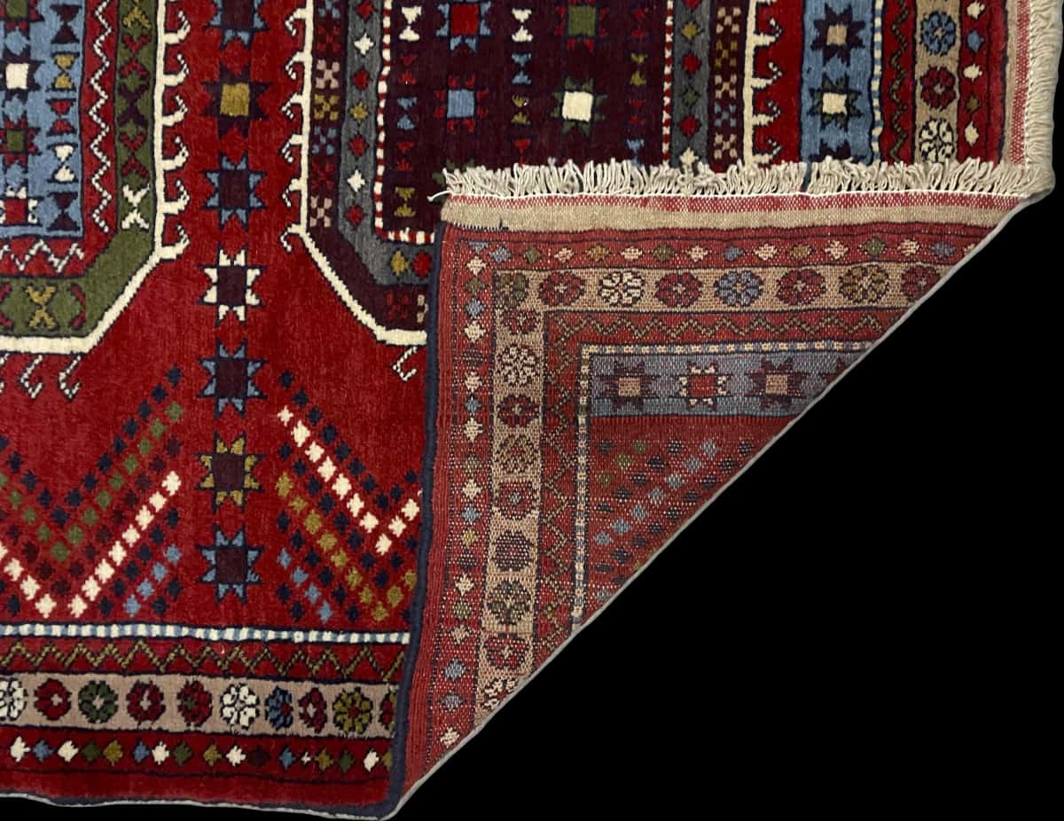 alfombra persa de estilo Quchan en dimensiones 165 centímetros de largo por 130 centímetros de ancho con colores principalmente rojo — Plegada