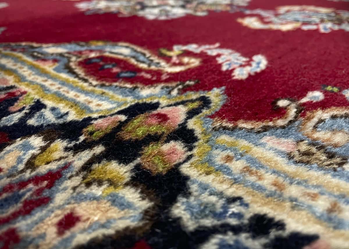 Persian rug of Kerman style in dimensions 145 centimeters length by 88 centimeters width with mainly red and blue colors — Texture close-up