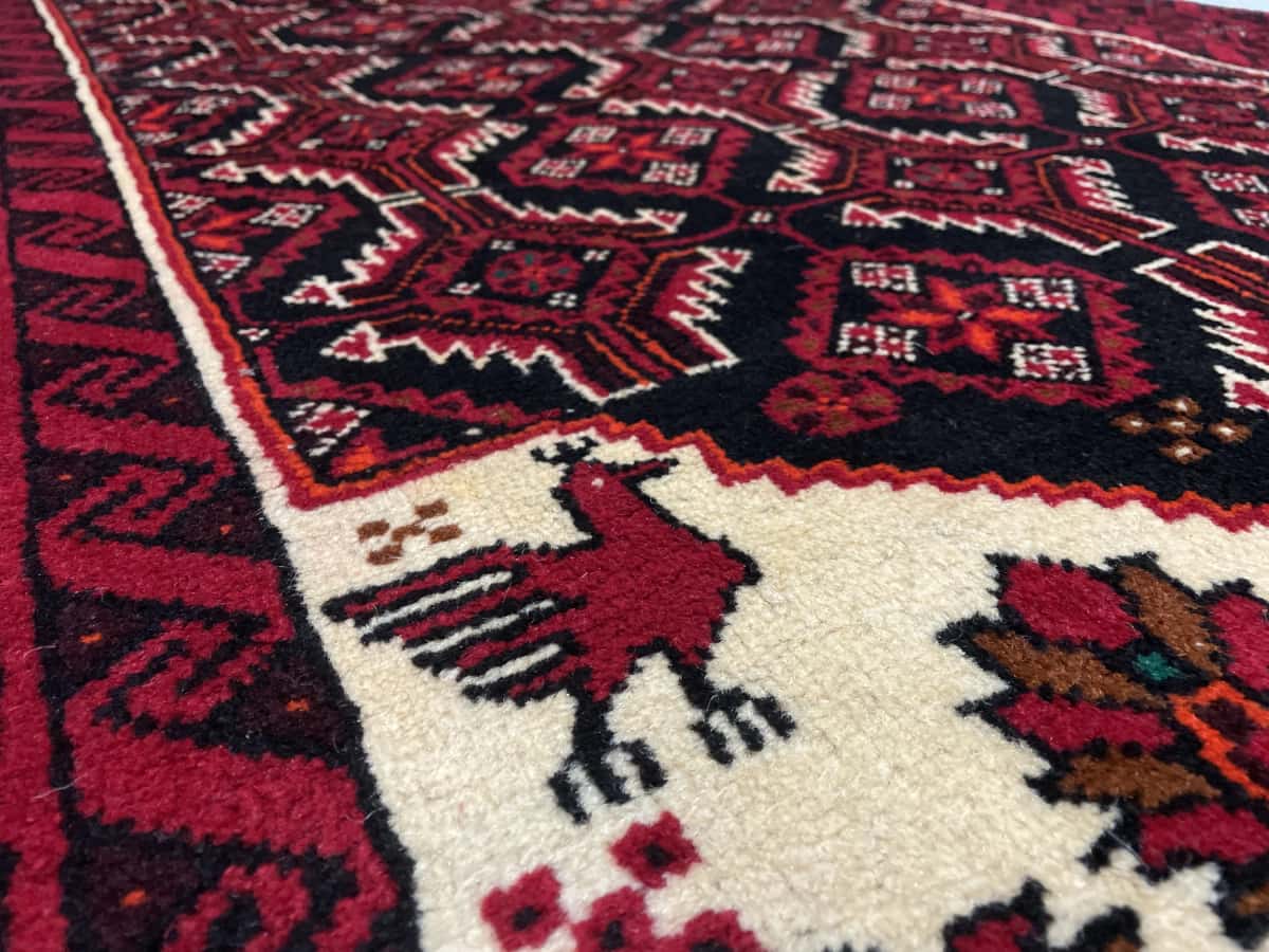 Persian rug of Baluch style in dimensions 194 centimeters length by 105 centimeters width with mainly red colors — Texture close-up