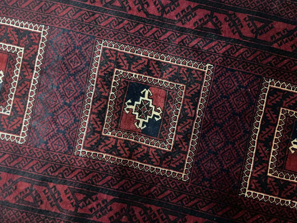 alfombra persa de estilo baluch en dimensiones 198 centímetros de largo por 110 centímetros de ancho con colores principalmente rojo — Primer plano de la textura