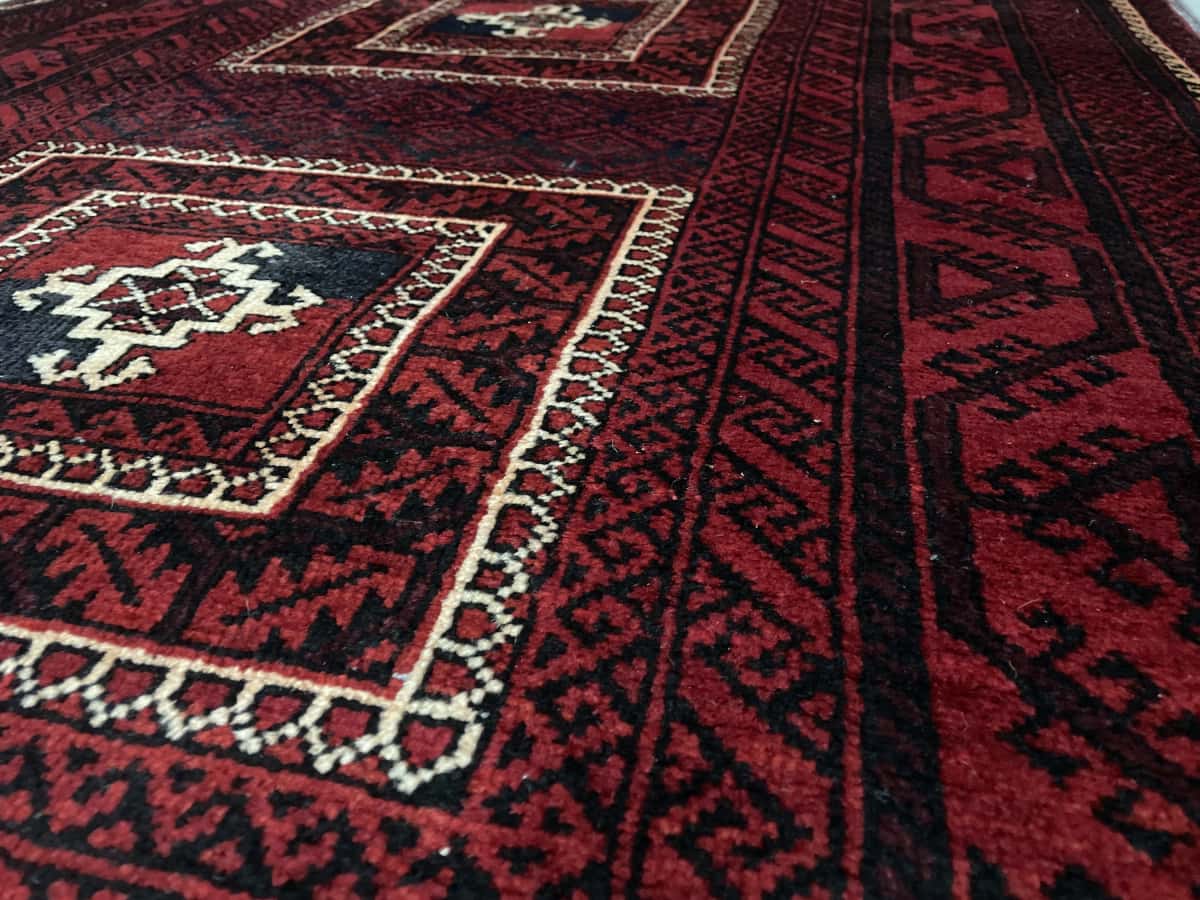 alfombra persa de estilo baluch en dimensiones 198 centímetros de largo por 110 centímetros de ancho con colores principalmente rojo — Primer plano de la textura