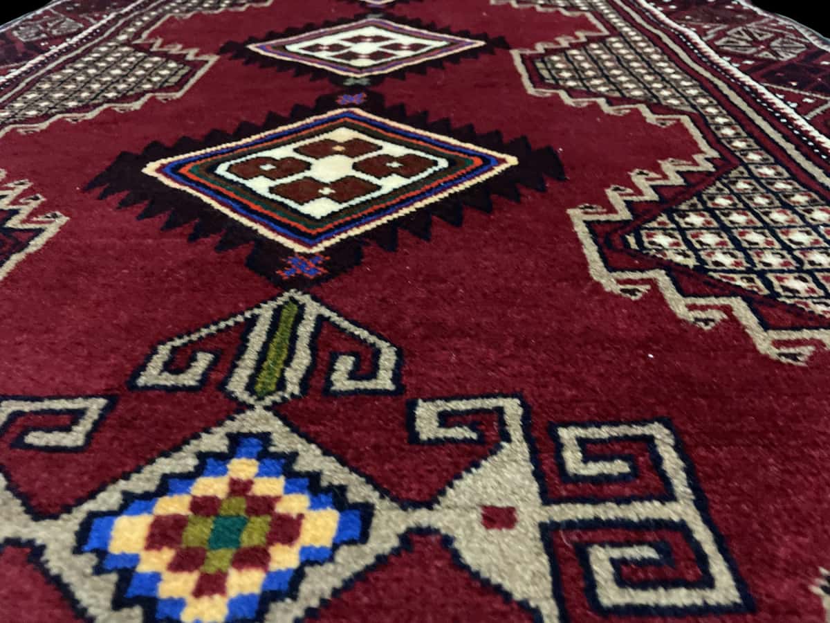 Persian rug of Baluch style in dimensions 195 centimeters length by 100 centimeters width with mainly red colors — Texture close-up