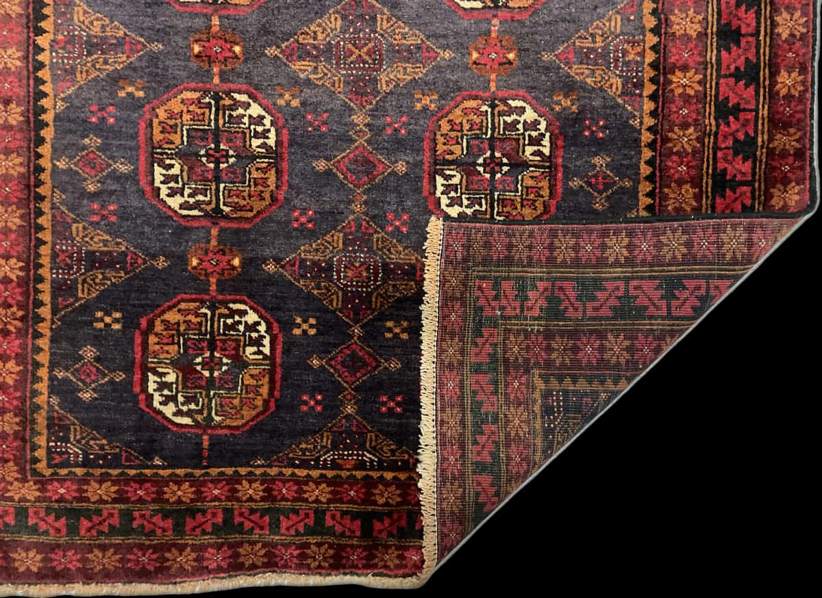 alfombra persa de estilo baluch en dimensiones 188 centímetros de largo por 116 centímetros de ancho con colores principalmente rojo — Plegada