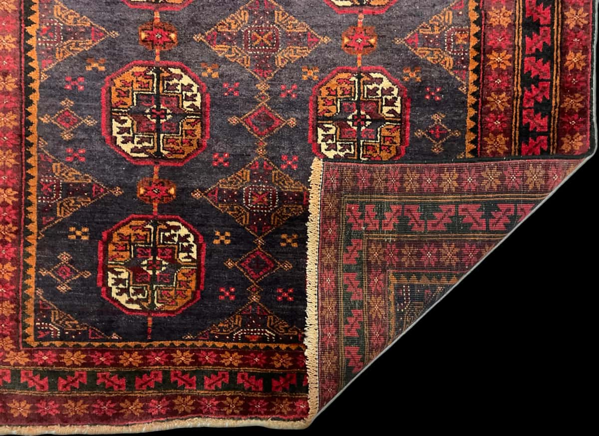 persischer Teppich im Baluch Stil in den Maßen 188 Zentimeter Länge mal 116 Zentimeter Breite mit überwiegend rot Farben — Gefaltet