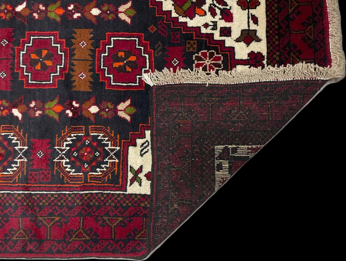 alfombra persa de estilo baluch en dimensiones 170 centímetros de largo por 103 centímetros de ancho con colores principalmente rojo — Plegada