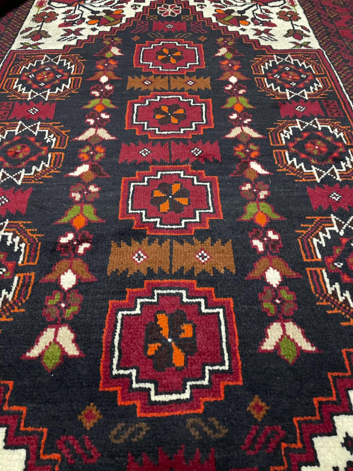 alfombra persa de estilo baluch en dimensiones 170 centímetros de largo por 103 centímetros de ancho con colores principalmente rojo — Primer plano de la textura