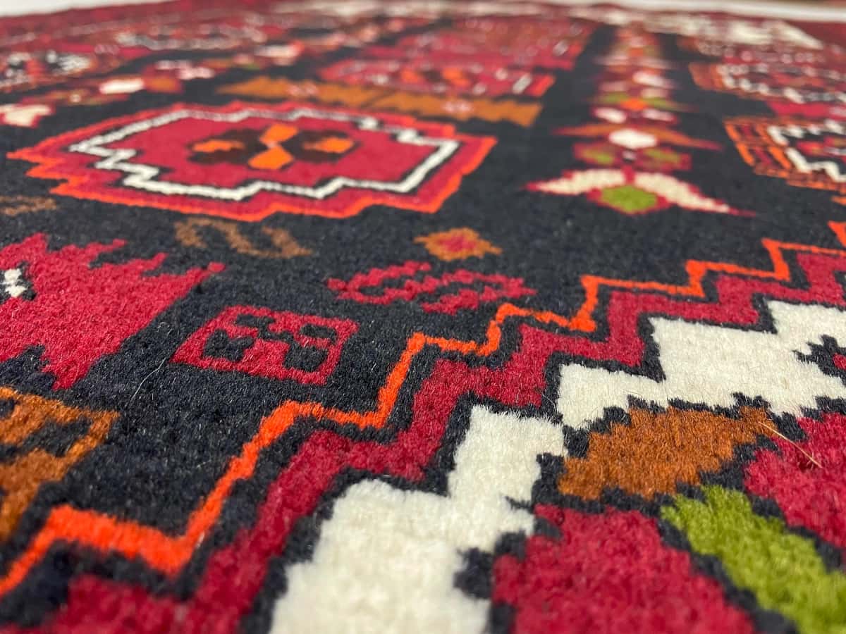 persischer Teppich im Baluch Stil in den Maßen 170 Zentimeter Länge mal 103 Zentimeter Breite mit überwiegend rot Farben — Nahaufnahme der Textur