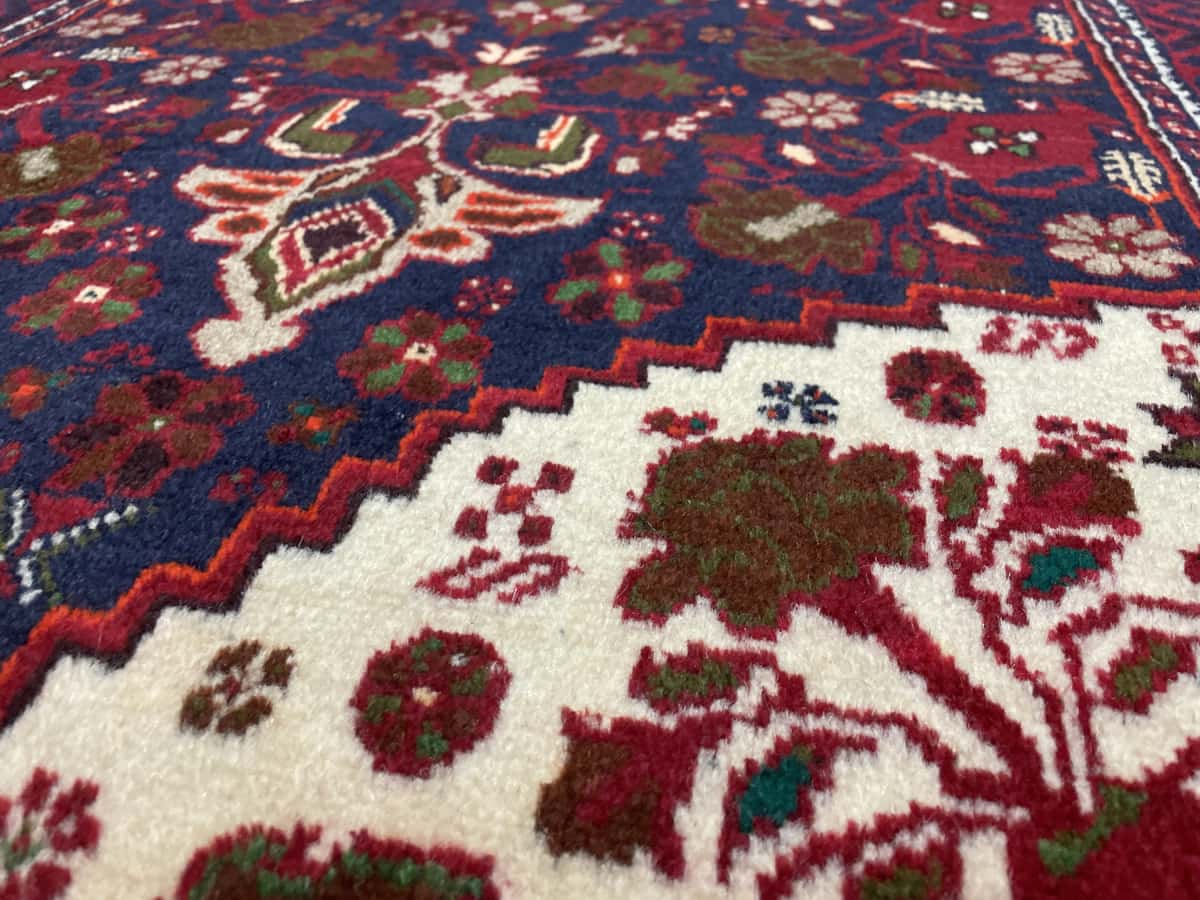 alfombra persa de estilo baluch en dimensiones 190 centímetros de largo por 104 centímetros de ancho con colores principalmente rojo — Primer plano de la textura