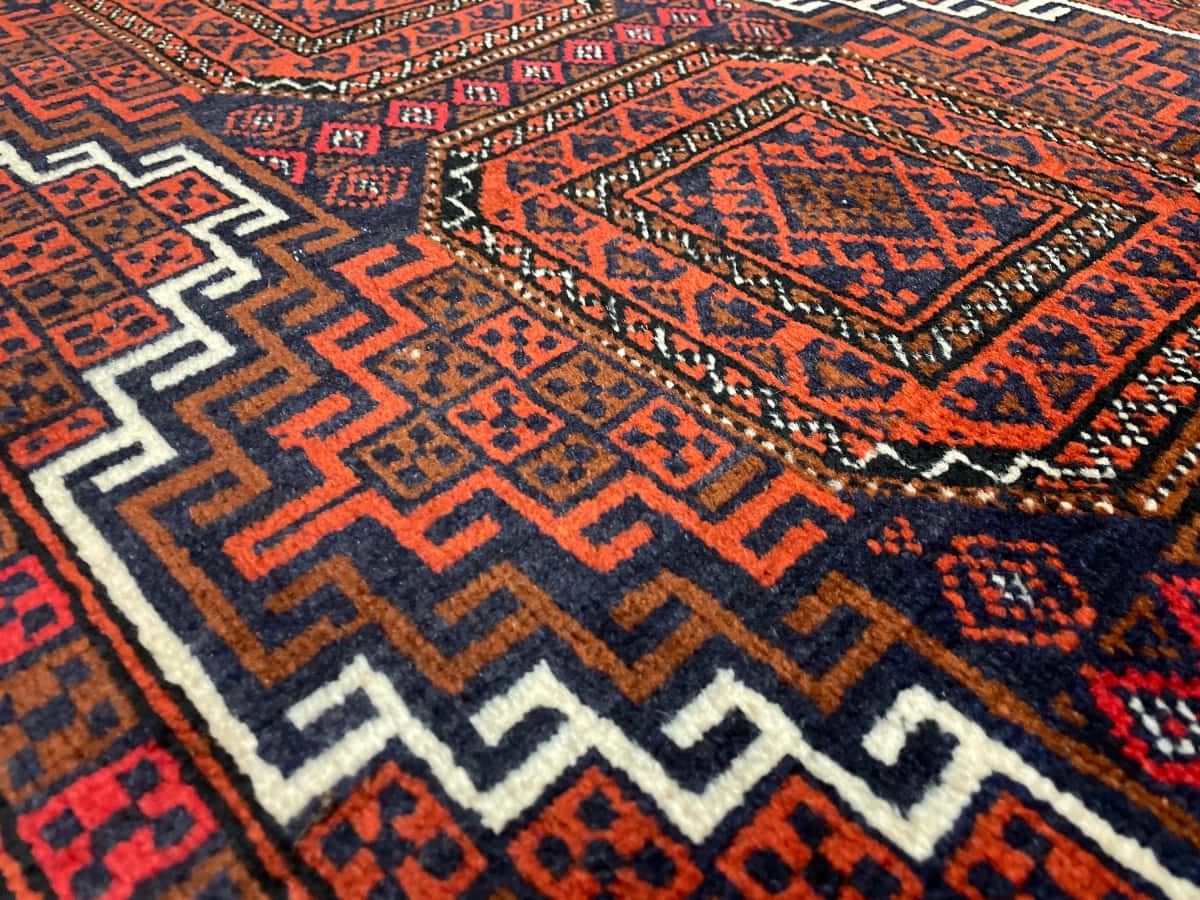 alfombra persa de estilo baluch en dimensiones 180 centímetros de largo por 98 centímetros de ancho con colores principalmente naranja — Primer plano de la textura