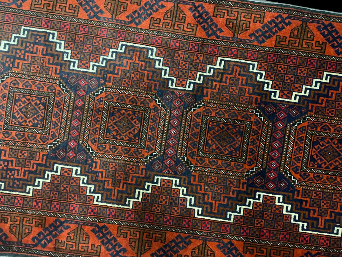 alfombra persa de estilo baluch en dimensiones 180 centímetros de largo por 98 centímetros de ancho con colores principalmente naranja — Perspectiva