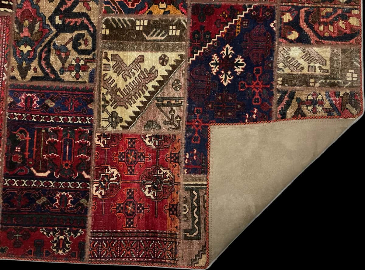 alfombra persa de estilo patchwork en dimensiones 178 centímetros de largo por 115 centímetros de ancho con colores principalmente rojo — Plegada