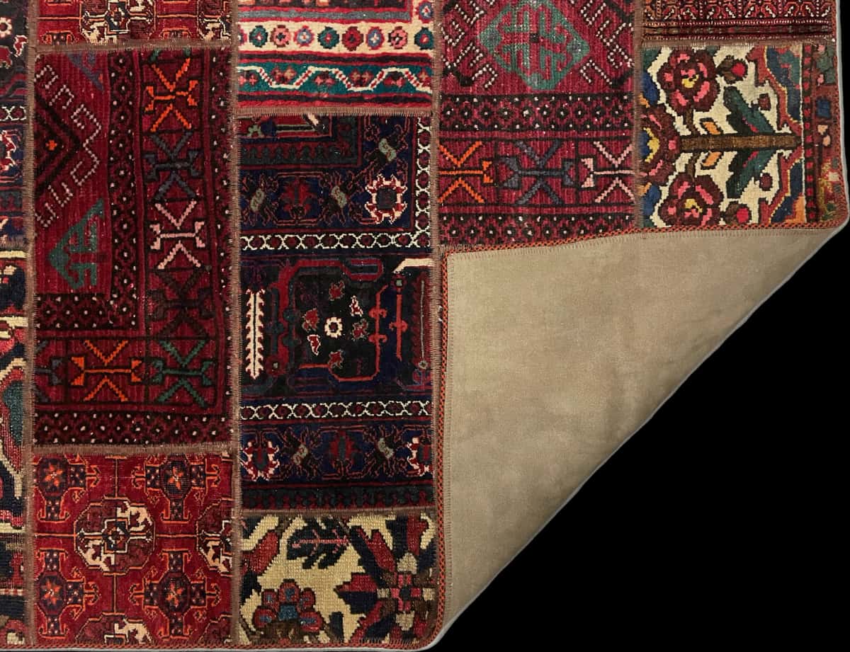 alfombra persa de estilo patchwork en dimensiones 179 centímetros de largo por 116 centímetros de ancho con colores principalmente rojo — Plegada