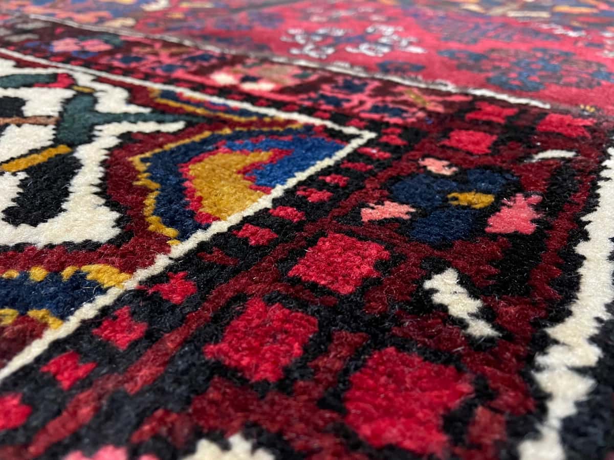 Persian rug of Rey style in dimensions 207 centimeters length by 136 centimeters width with mainly red colors — Texture close-up