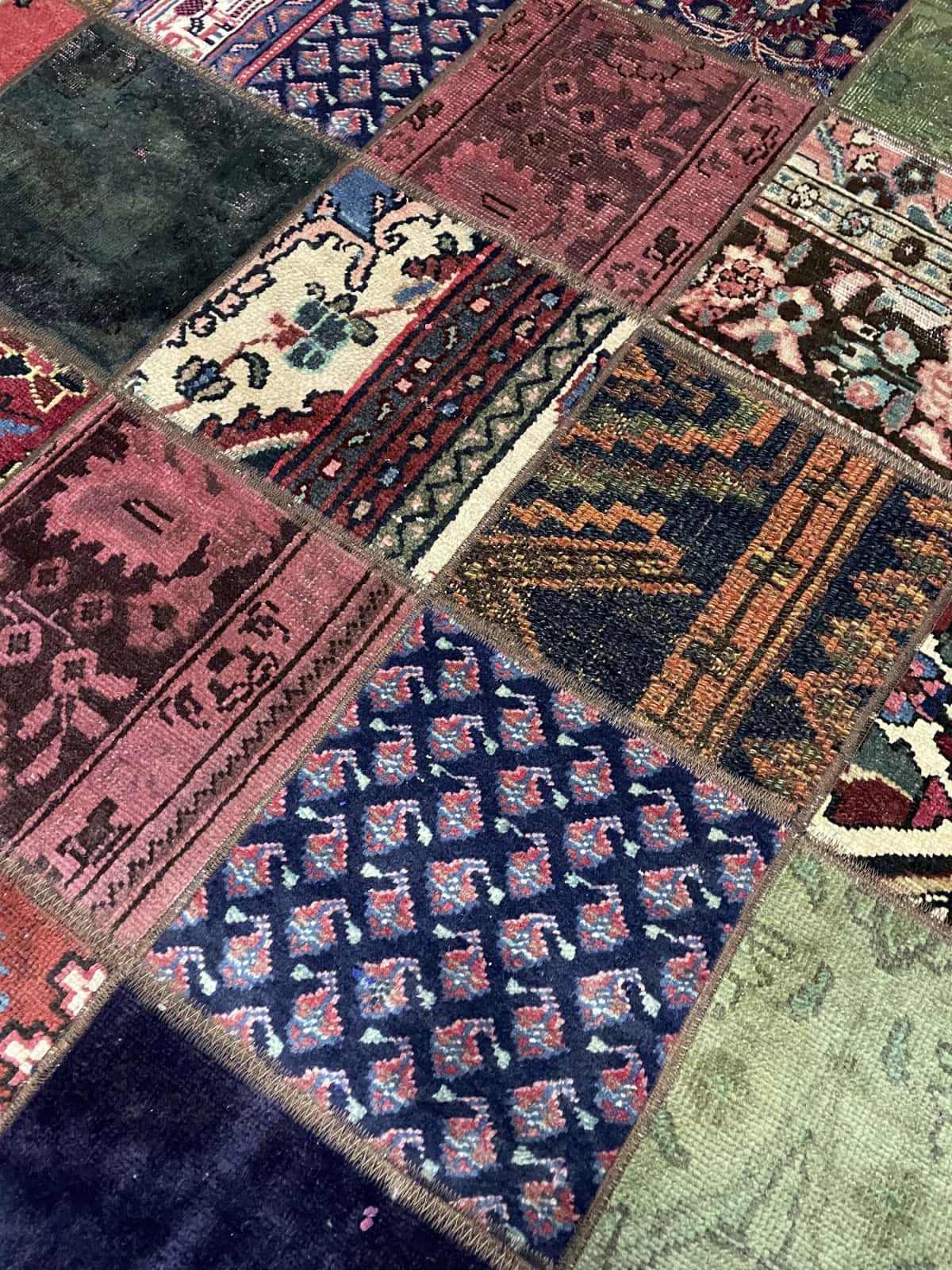 alfombra persa de estilo patchwork en dimensiones 212 centímetros de largo por 151 centímetros de ancho con colores principalmente rojo y verde — Primer plano de la textura
