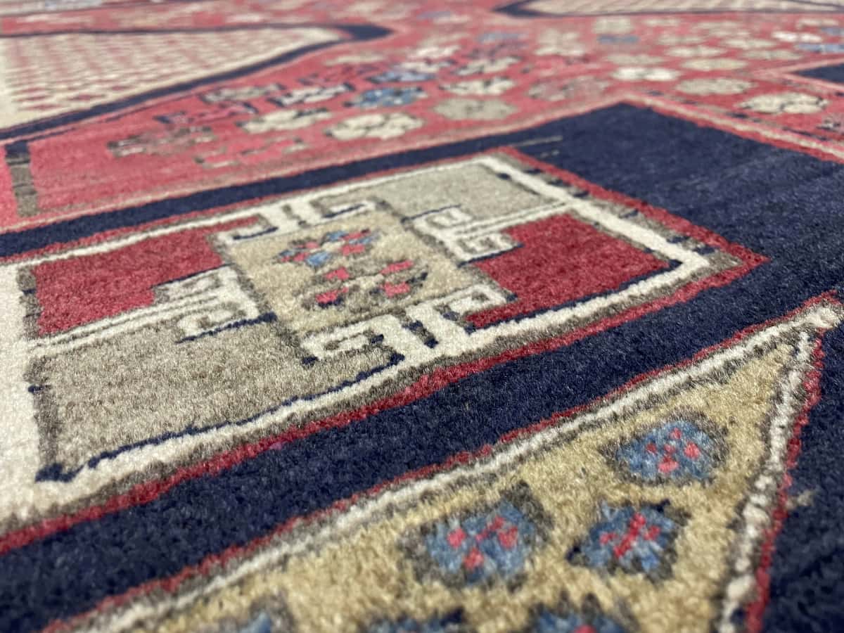 Persian rug of Meshginshahr style in dimensions 134 centimeters length by 116 centimeters width with mainly blue and red colors — Texture close-up