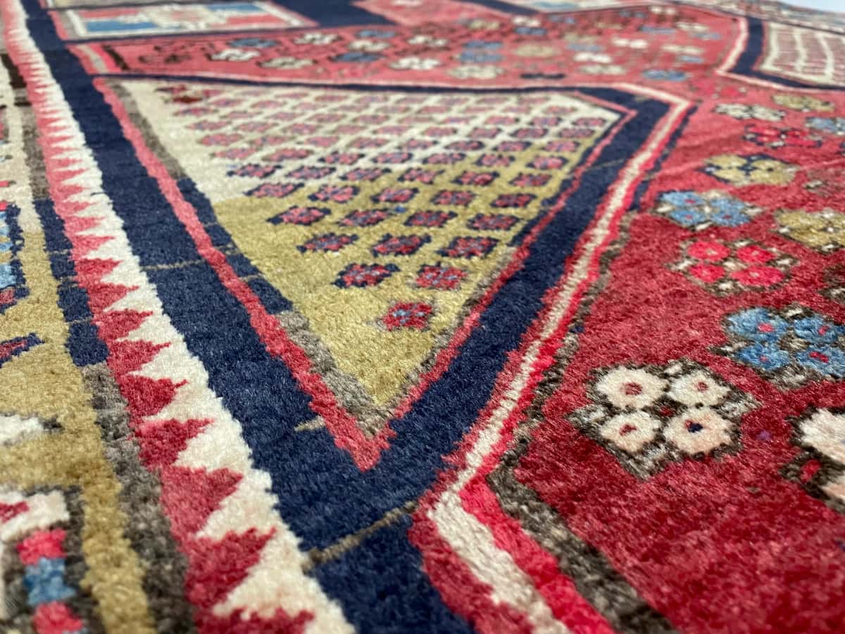 persischer Teppich im Meshginshahr Stil in den Maßen 143 Zentimeter Länge mal 111 Zentimeter Breite mit überwiegend rot und blau Farben — Nahaufnahme der Textur