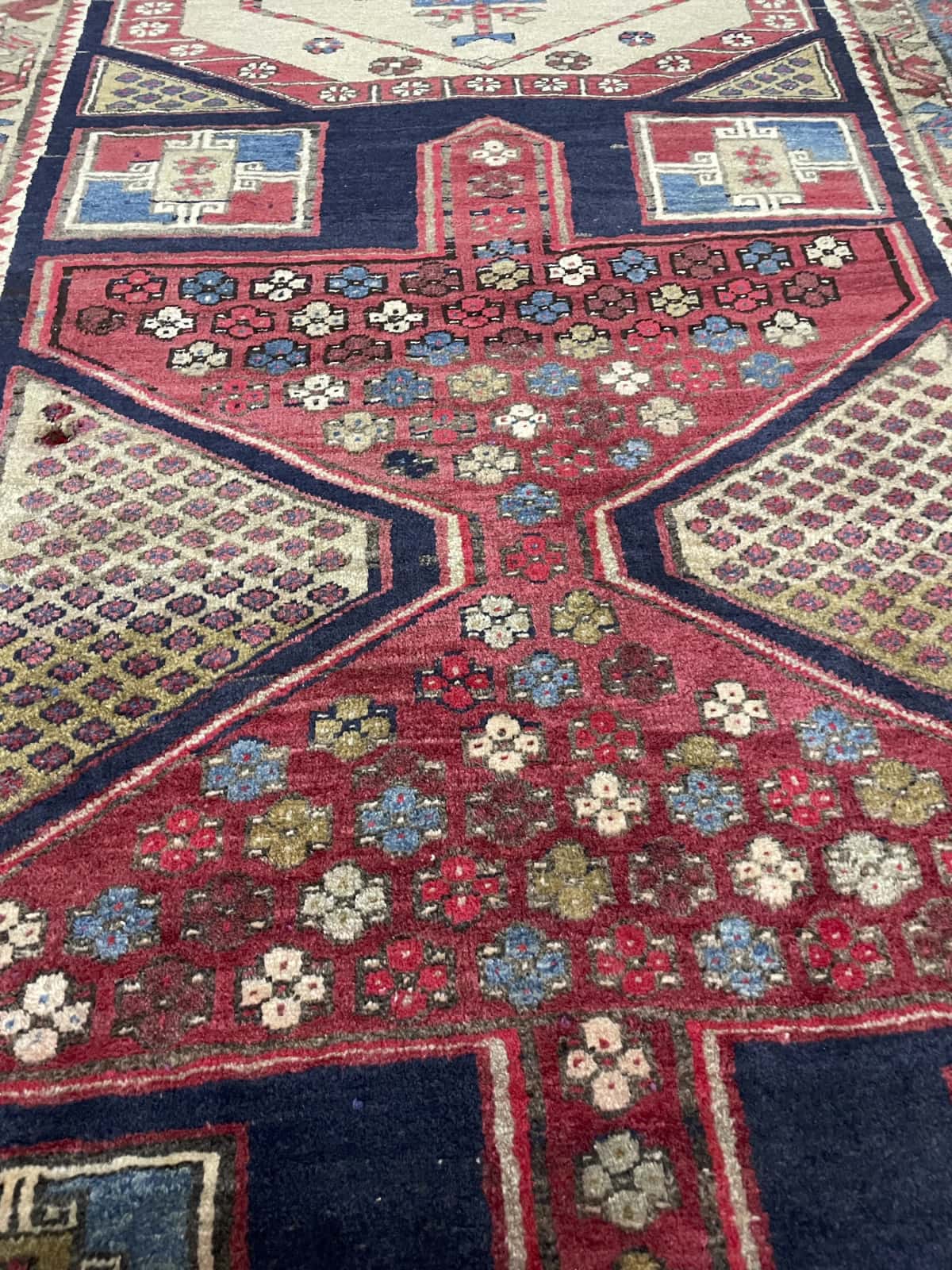 alfombra persa de estilo Meshginshahr en dimensiones 143 centímetros de largo por 111 centímetros de ancho con colores principalmente rojo y azul — Primer plano de la textura