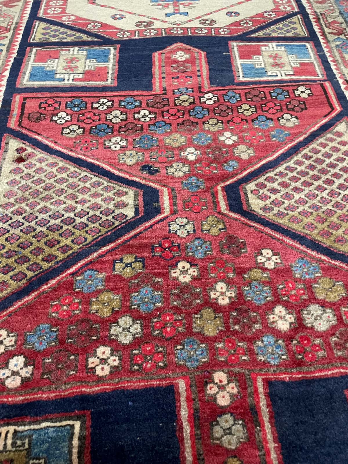 persischer Teppich im Meshginshahr Stil in den Maßen 143 Zentimeter Länge mal 111 Zentimeter Breite mit überwiegend rot und blau Farben — Nahaufnahme der Textur