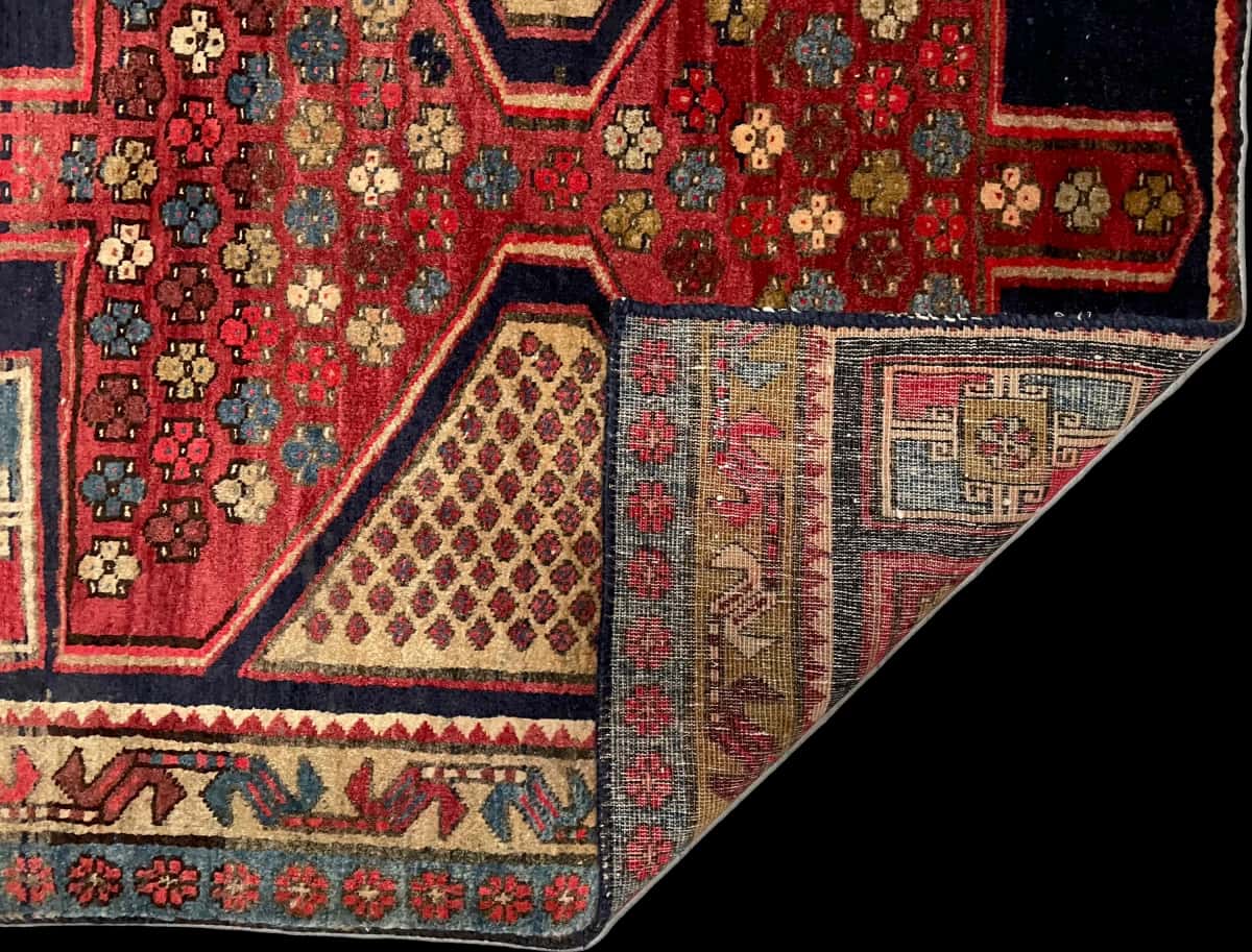 persischer Teppich im Meshginshahr Stil in den Maßen 143 Zentimeter Länge mal 111 Zentimeter Breite mit überwiegend rot und blau Farben — Gefaltet