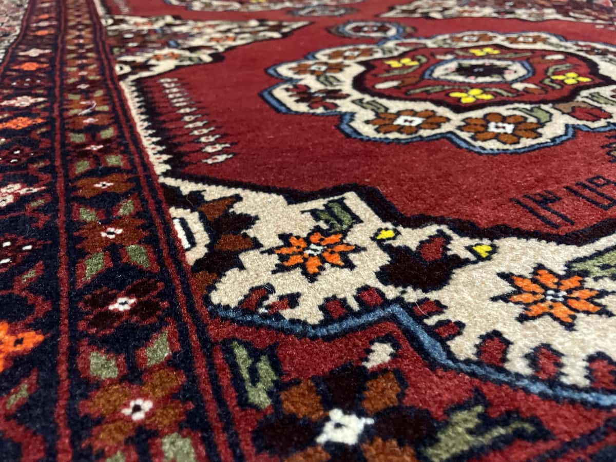 Persian rug of Baluch style in dimensions 198 centimeters length by 111 centimeters width with mainly red and orange colors — Texture close-up