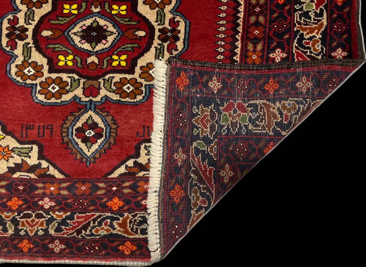 persischer Teppich im Baluch Stil in den Maßen 198 Zentimeter Länge mal 111 Zentimeter Breite mit überwiegend rot und orange Farben — Gefaltet