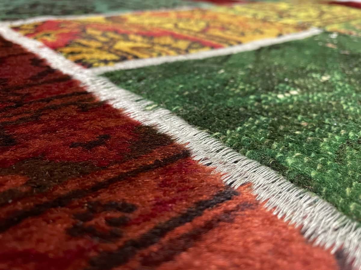 alfombra persa de estilo patchwork en dimensiones 200 centímetros de largo por 136 centímetros de ancho con colores principalmente rojo y verde — Primer plano de la textura