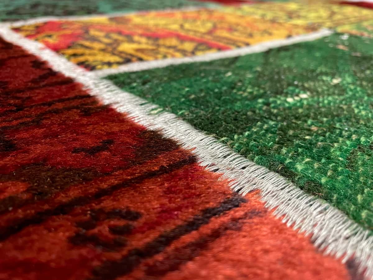 persischer Teppich im Rey Stil in den Maßen 200 Zentimeter Länge mal 136 Zentimeter Breite mit überwiegend rot und grün Farben — Nahaufnahme der Textur
