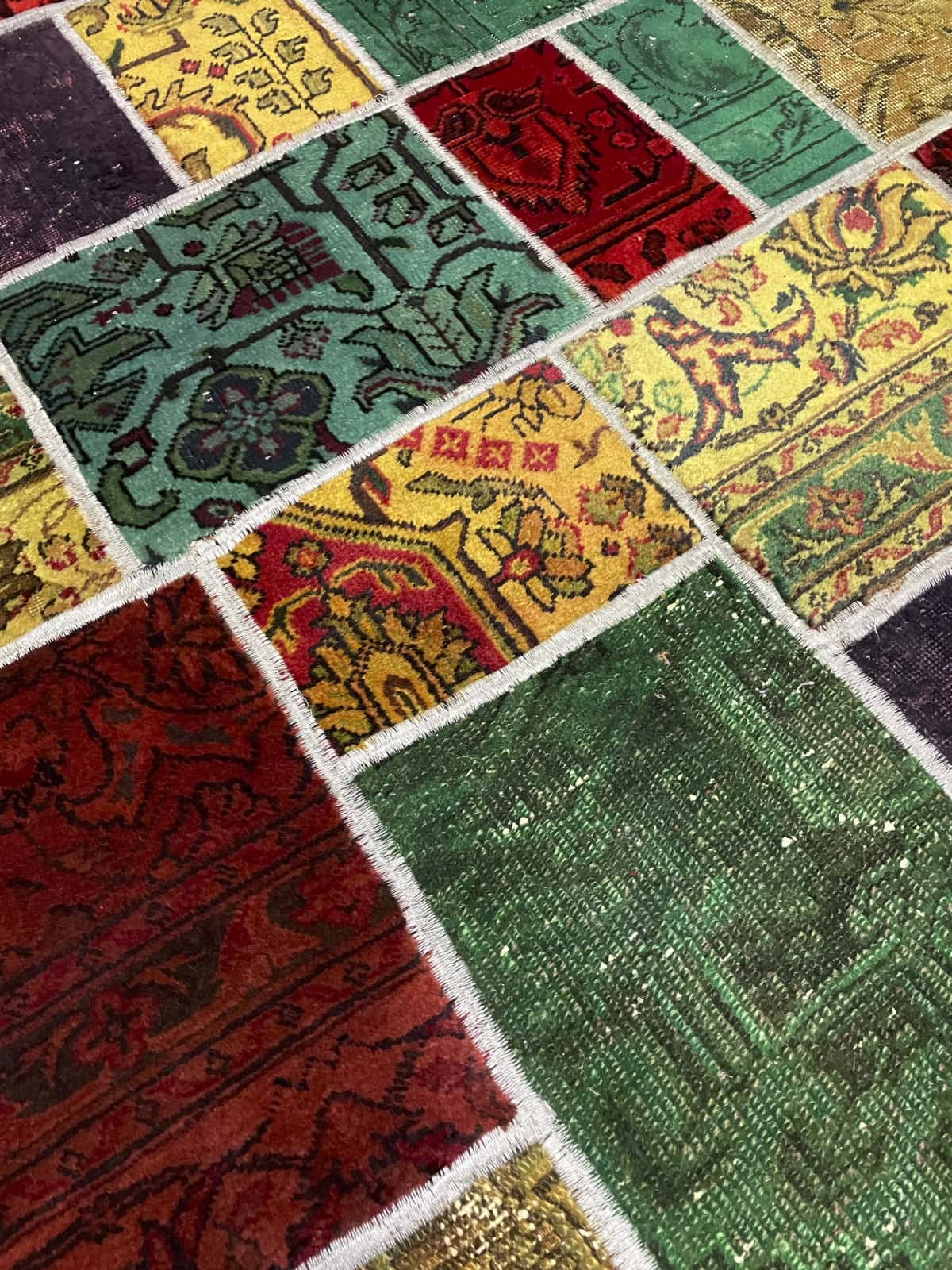 alfombra persa de estilo patchwork en dimensiones 200 centímetros de largo por 136 centímetros de ancho con colores principalmente rojo y verde — Primer plano de la textura
