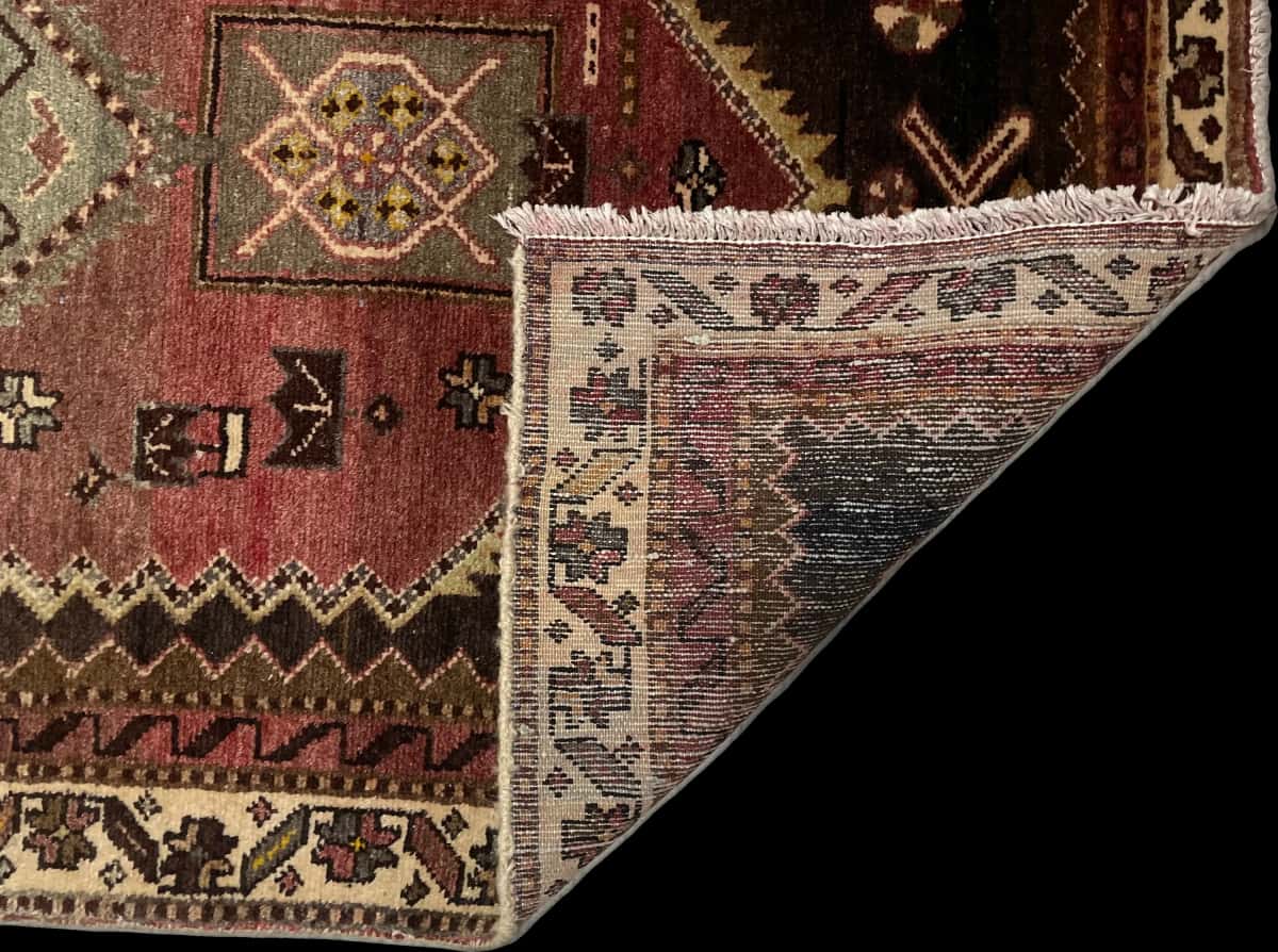 persischer Teppich im Zanjan Stil in den Maßen 215 Zentimeter Länge mal 100 Zentimeter Breite mit überwiegend grün und braun Farben — Gefaltet