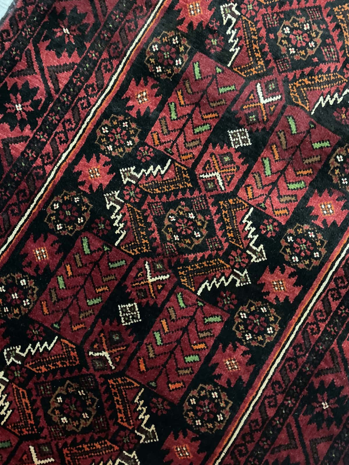 Persian rug of Baluch style in dimensions 212 centimeters length by 110 centimeters width with mainly red colors — Texture close-up