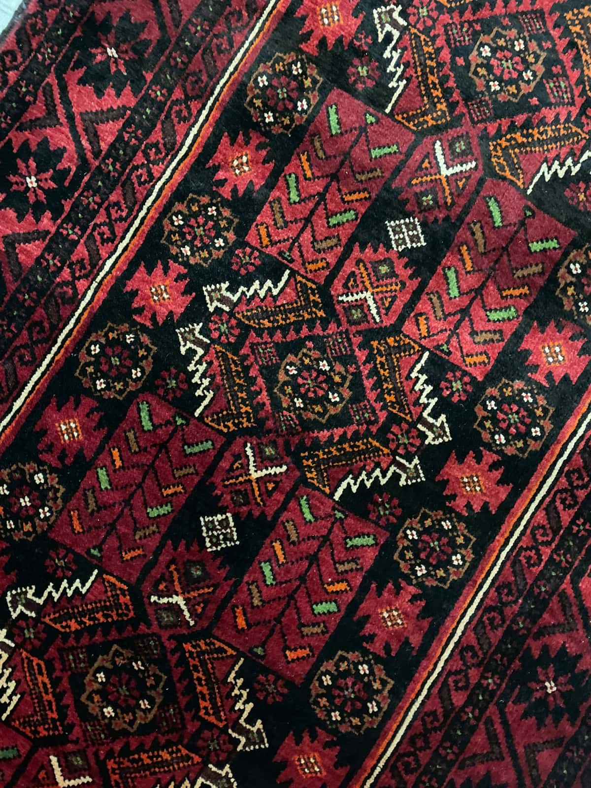 Persian rug of Baluch style in dimensions 212 centimeters length by 110 centimeters width with mainly red colors — Texture close-up