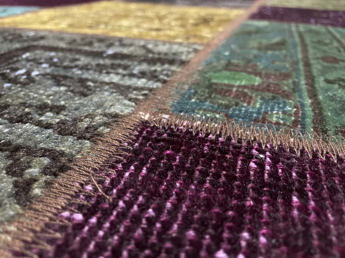 alfombra persa de estilo patchwork en dimensiones 172 centímetros de largo por 150 centímetros de ancho con colores principalmente verde y morado — Primer plano de la textura