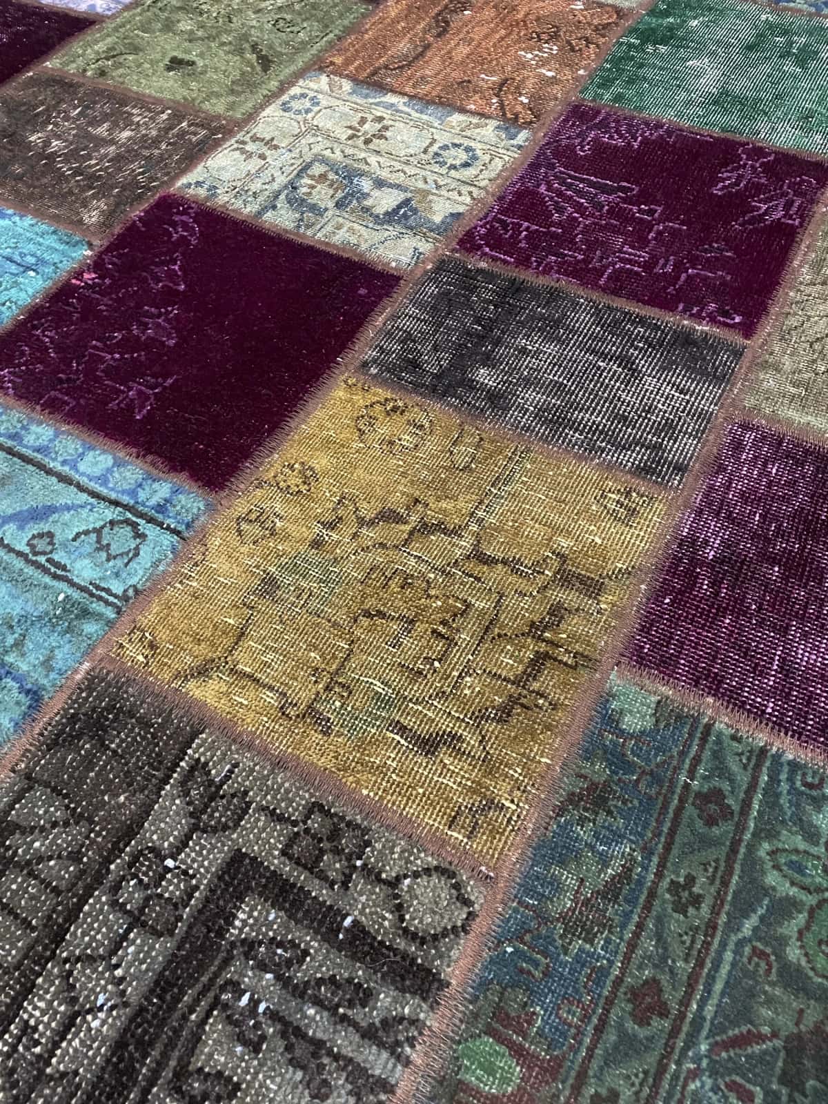 alfombra persa de estilo patchwork en dimensiones 172 centímetros de largo por 150 centímetros de ancho con colores principalmente verde y morado — Primer plano de la textura